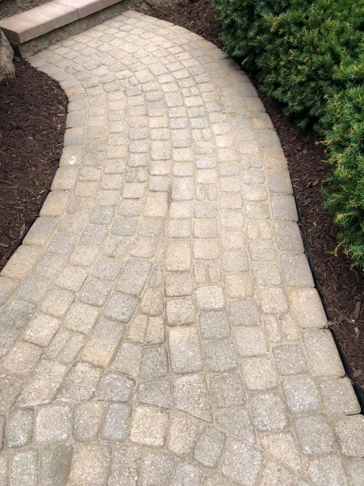 Curved stone paver walkway bordered by mulch and green shrubs