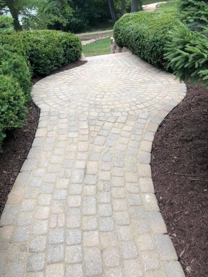 Curved light stone garden path bordered by dark mulch and green hedges