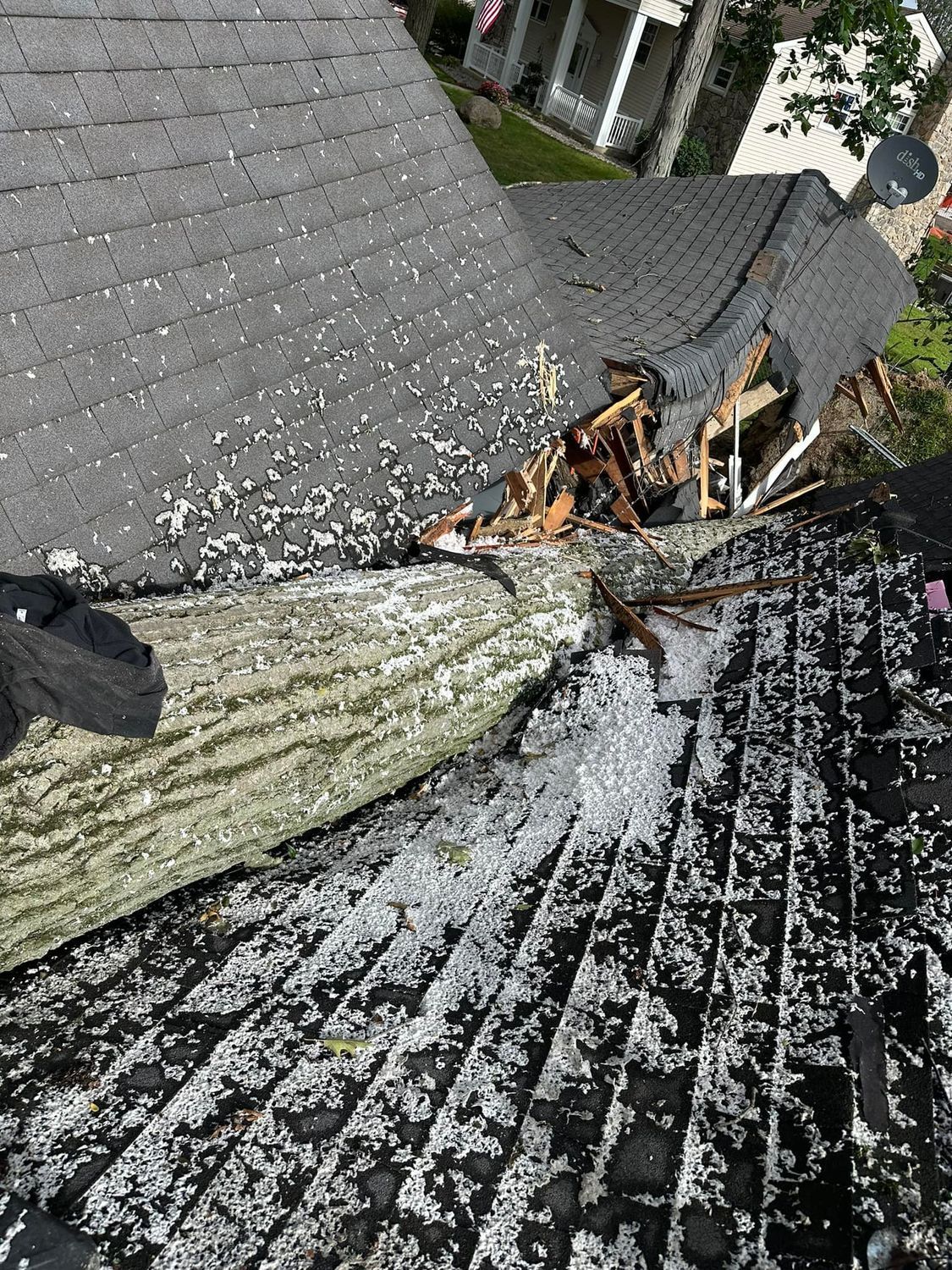 Damaged roof corner with broken shingles, exposed wood, and scattered debris near gutters