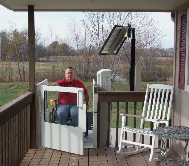 Man in a wheelchair using a porch-mounted lift on a wooden deck Man in a wheelchair using a porch-mounted lift on a wooden deck