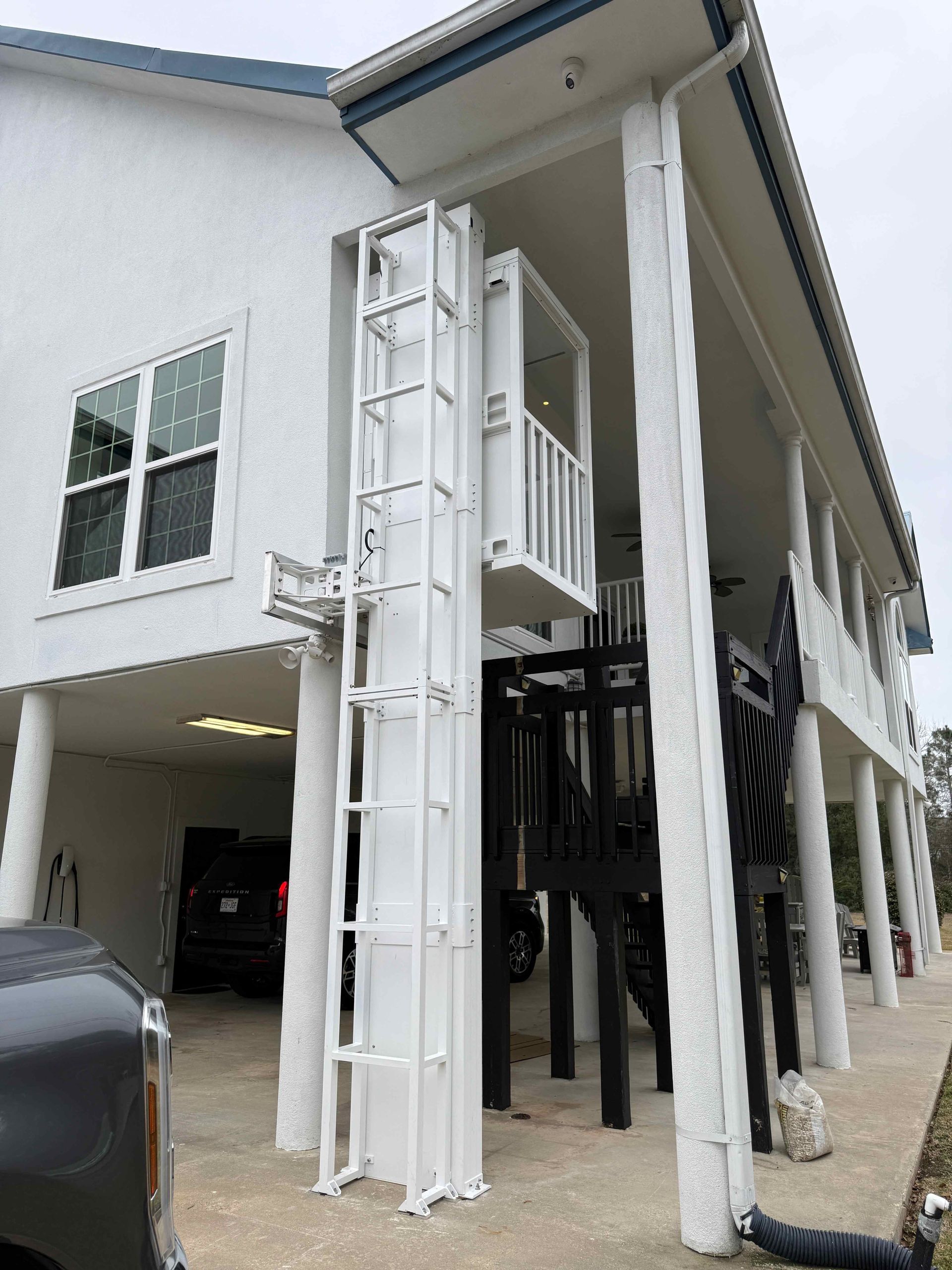House on raised stilts with a white exterior and exterior stairs under a covered porch