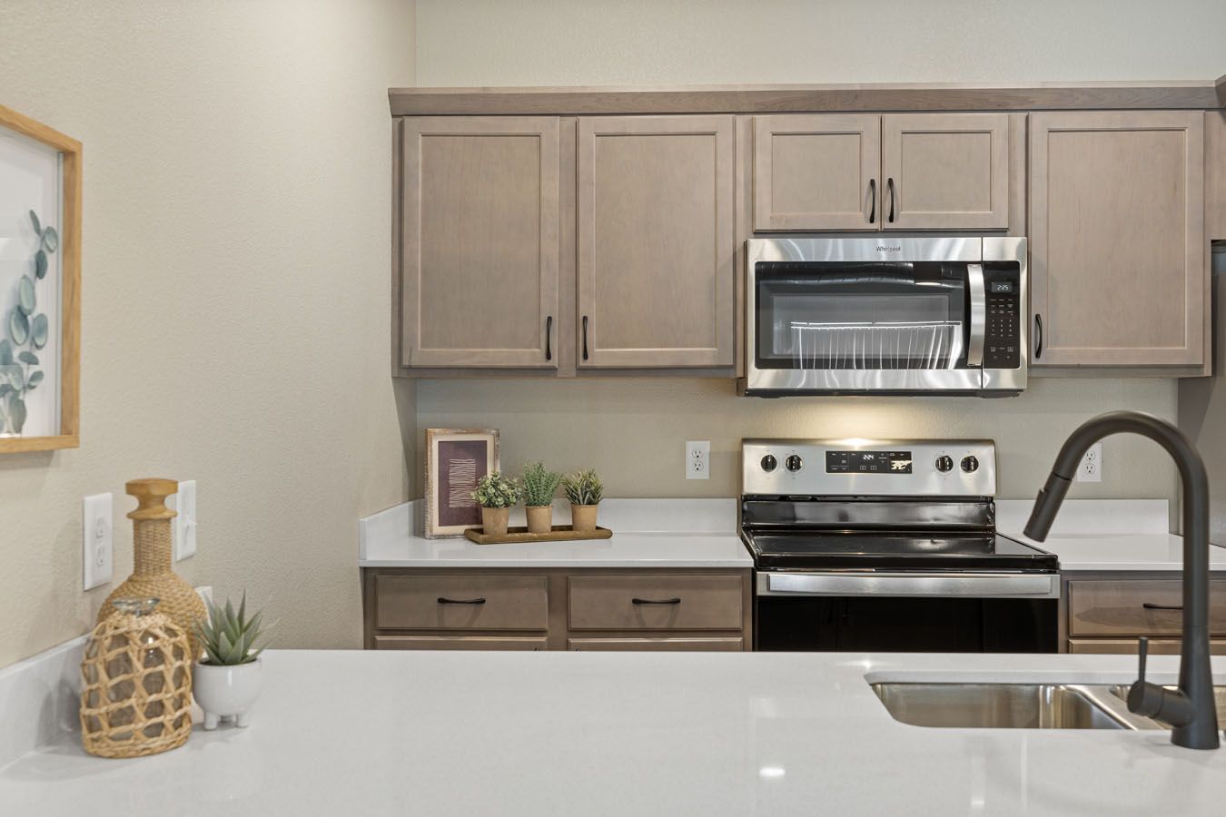 a kitchen with a stove , microwave , sink and cabinets .
