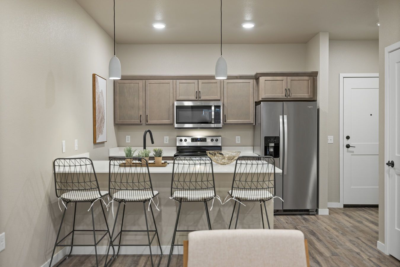 a kitchen with a stainless steel refrigerator , microwave , and sink .
