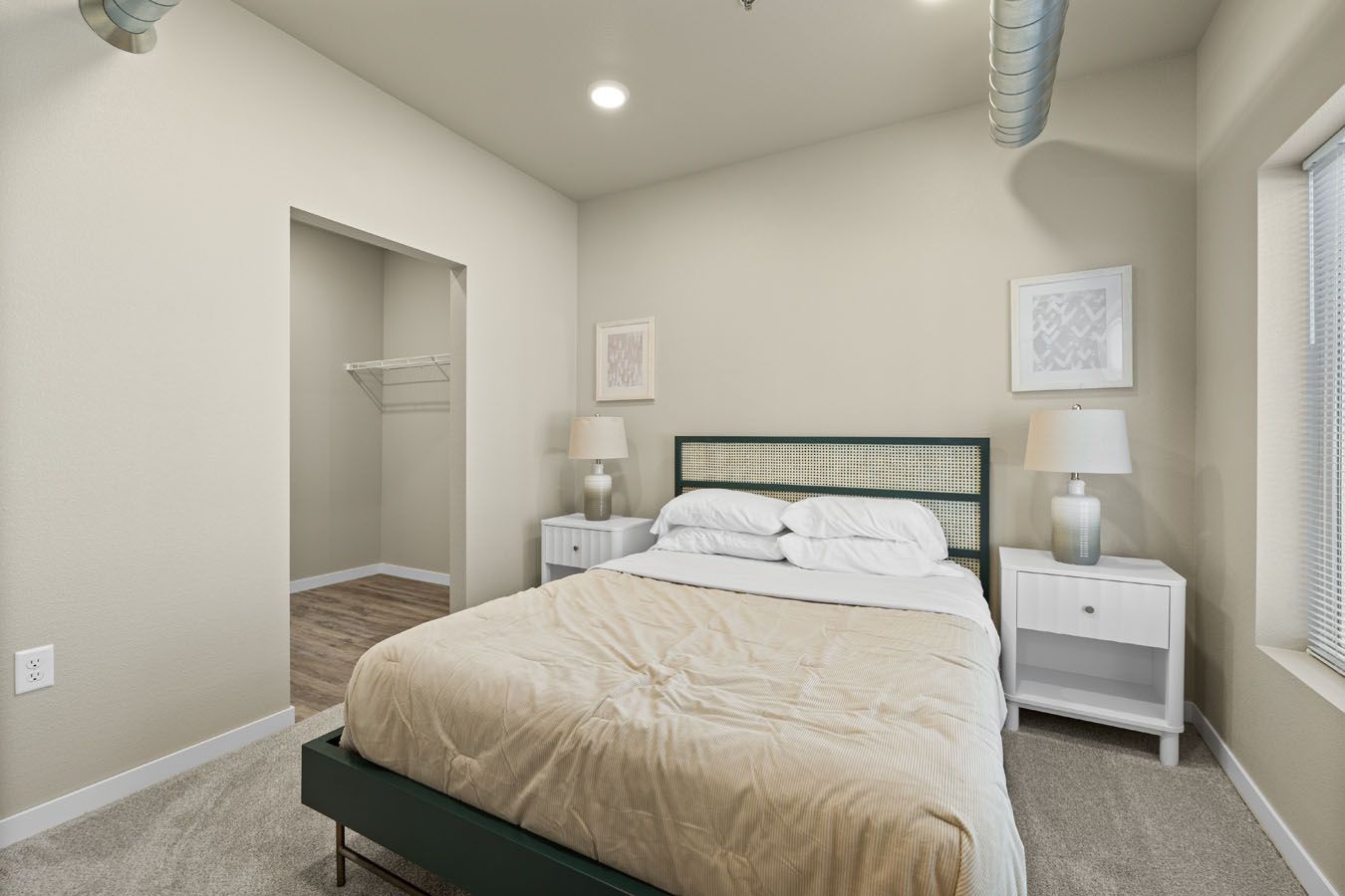 a bedroom with a bed , nightstands , lamps and a walk in closet .