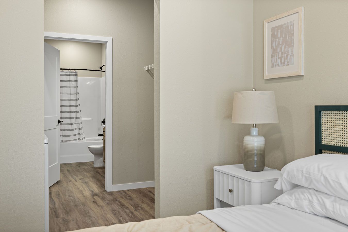 a bedroom with a bed , nightstand , lamp and bathroom .