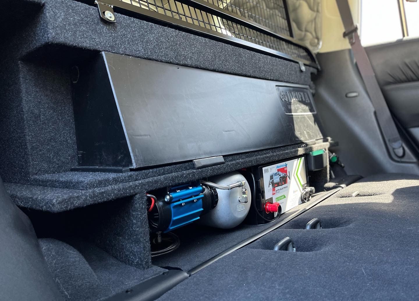 4WD rear storage system with onboard air compressor and auxiliary battery setup for off-road touring and camping.