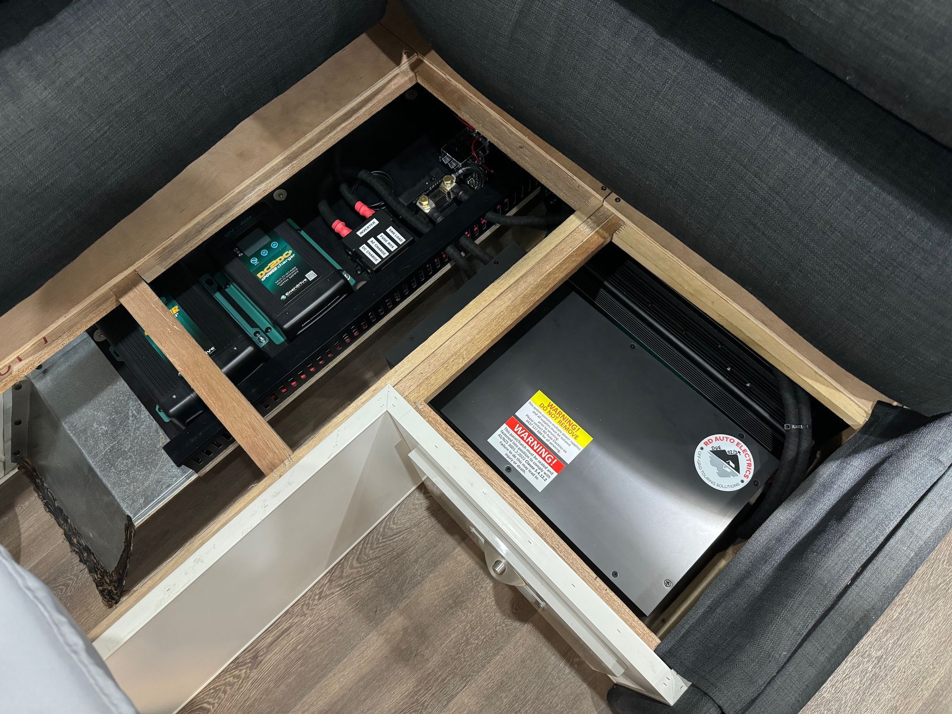 Under-seat lithium battery and inverter system installed in caravan lounge for hidden off-grid power and energy management.