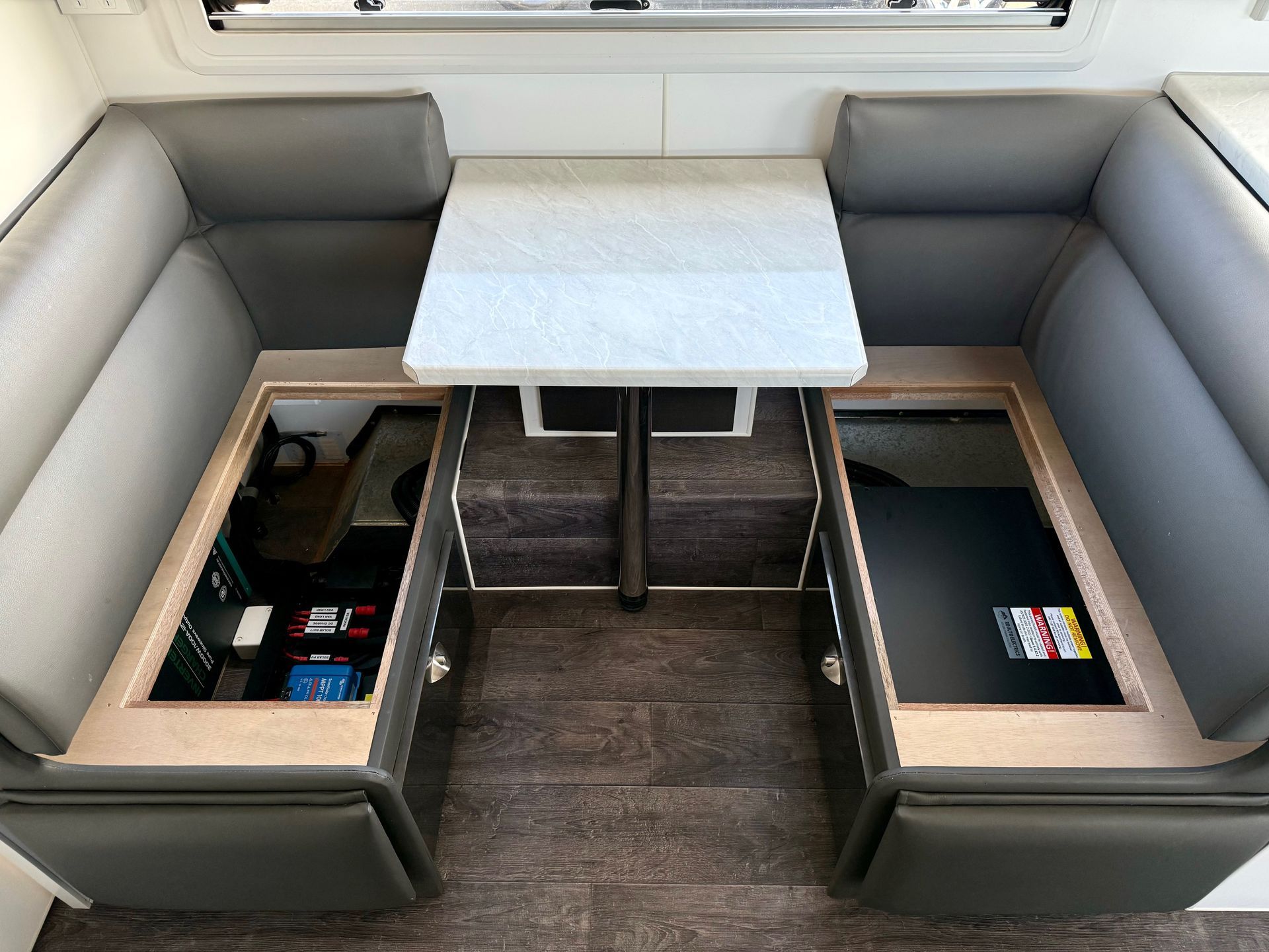 Under-seat lithium battery and power system installed in caravan dinette for hidden off-grid energy storage and management.
