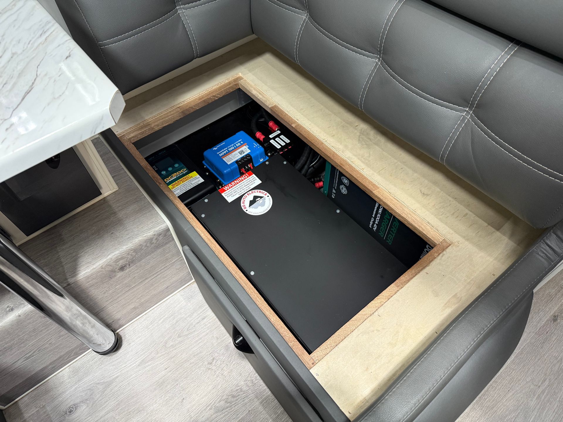 Space-saving under-seat power setup in caravan featuring lithium battery and charging system.
