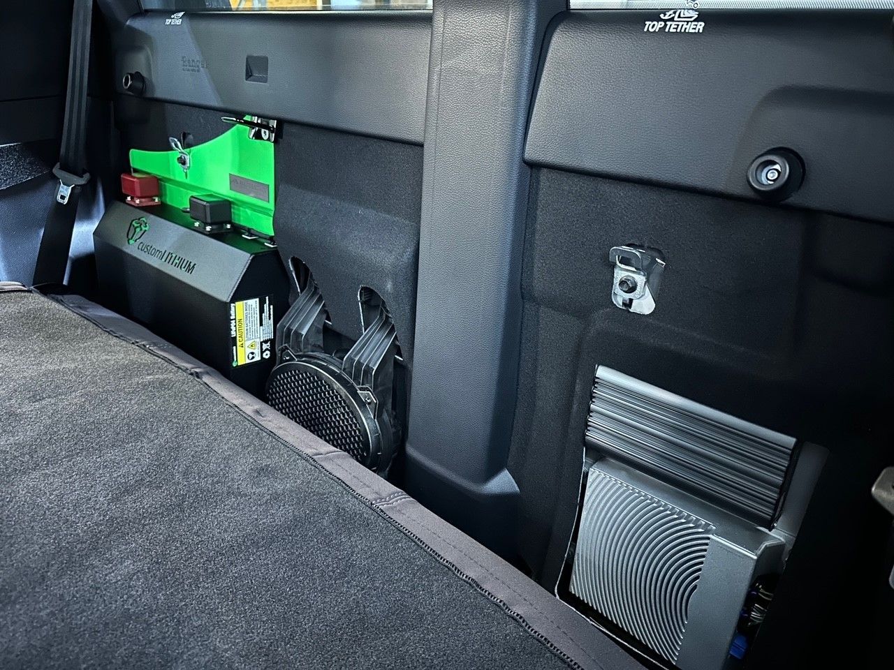 Custom lithium battery system mounted behind rear seat in dual cab ute for off-grid 12V power and touring electrics.
