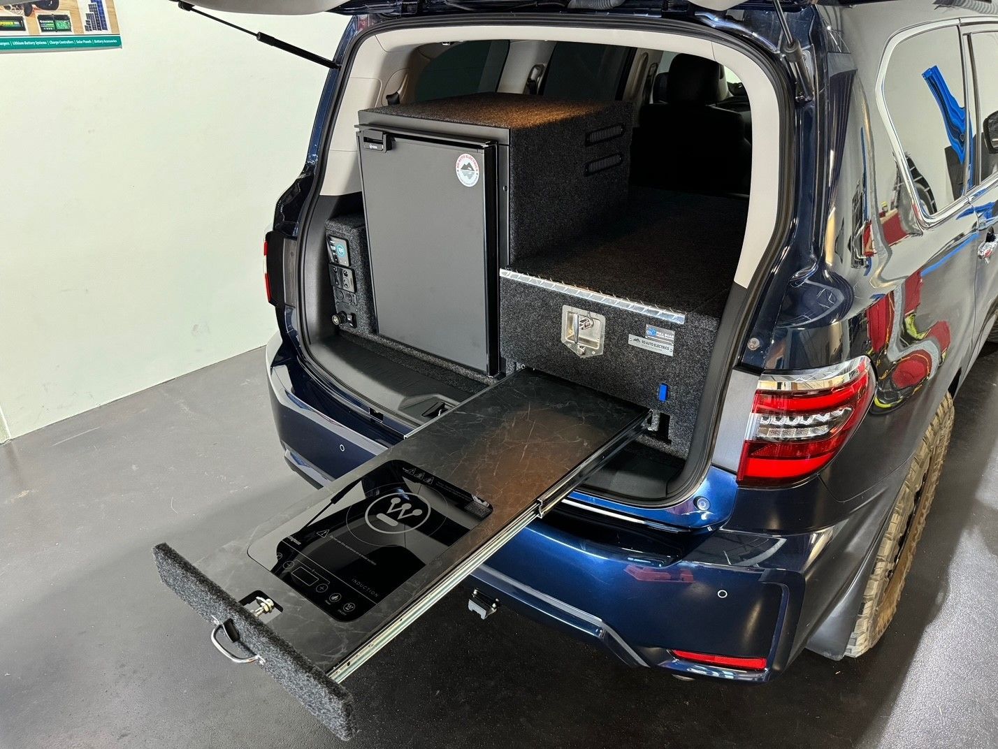 4WD touring drawer system with upright Bushman fridge and induction cooktop kitchen setup for off-grid camping and travel.