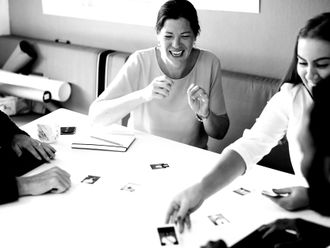 A group of people are sitting around a table playing cards.