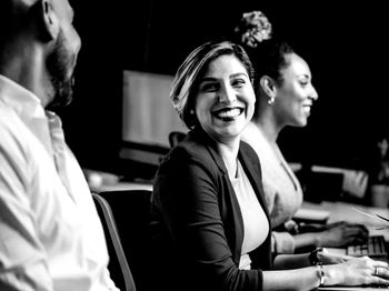 A group of people are sitting at a table with computers and smiling.
