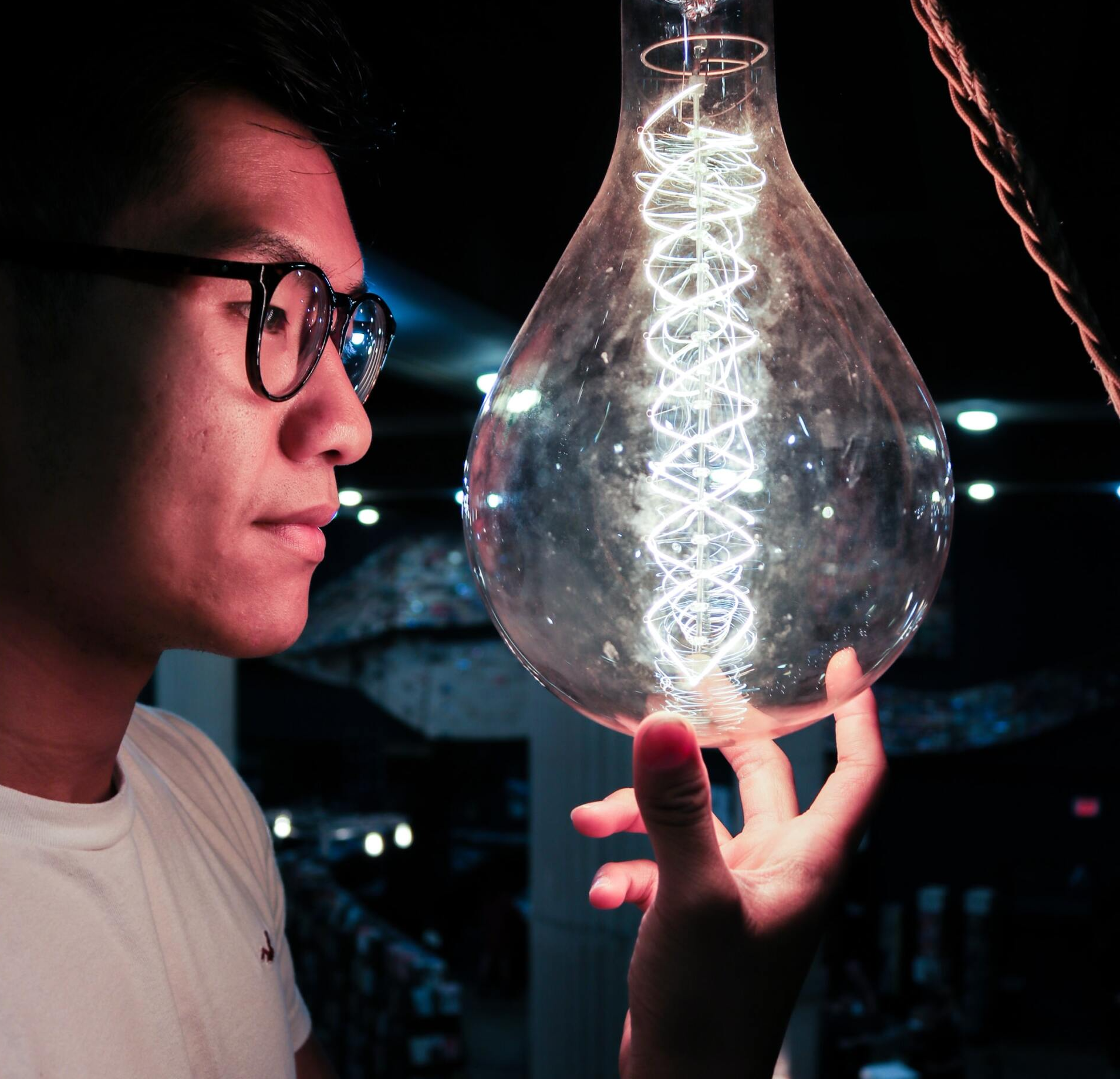 A man with glasses is holding a light bulb in his hand