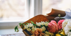 Bouquet of colorful flowers wrapped in brown paper near a bright window