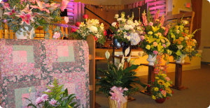 Flower arrangements and bouquets displayed in a decorated indoor memorial or ceremony space