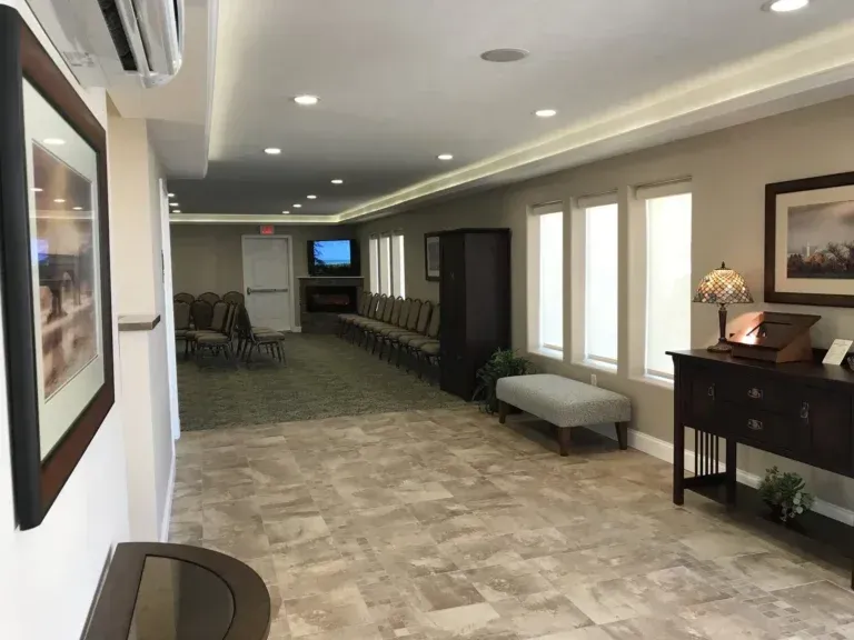 Empty hallway with chairs, bench, and framed art in a beige-walled lobby