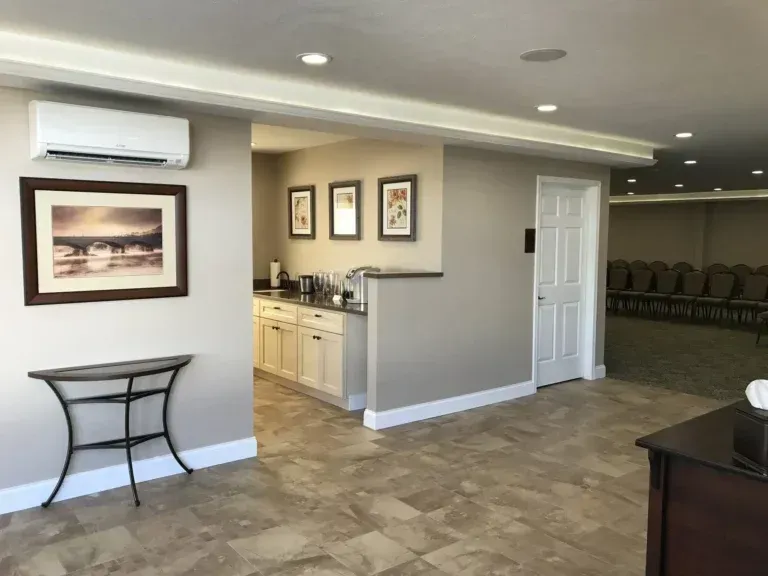 Spacious lobby with wall art, side table, air conditioner, and chairs in the background