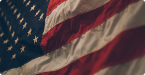 Close-up of an American flag waving, with red and white stripes and white stars on a blue field