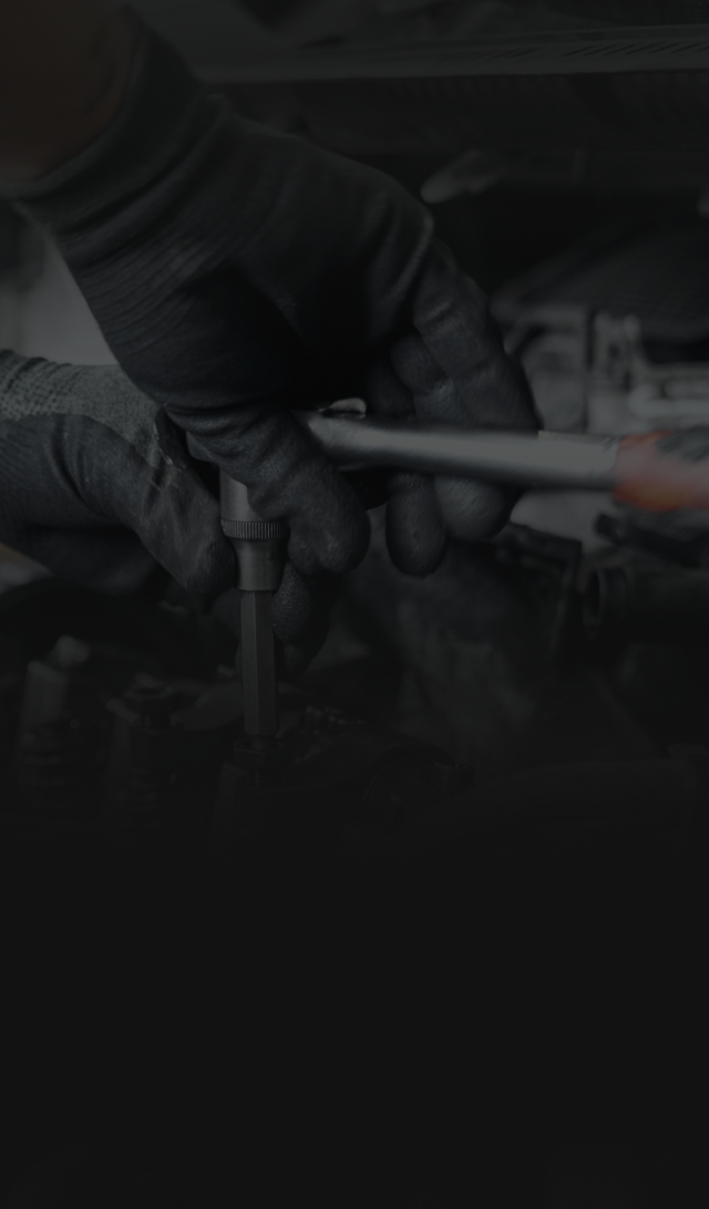 Mechanic's gloved hands using a wrench to work on a car engine. | ECP Auto Service