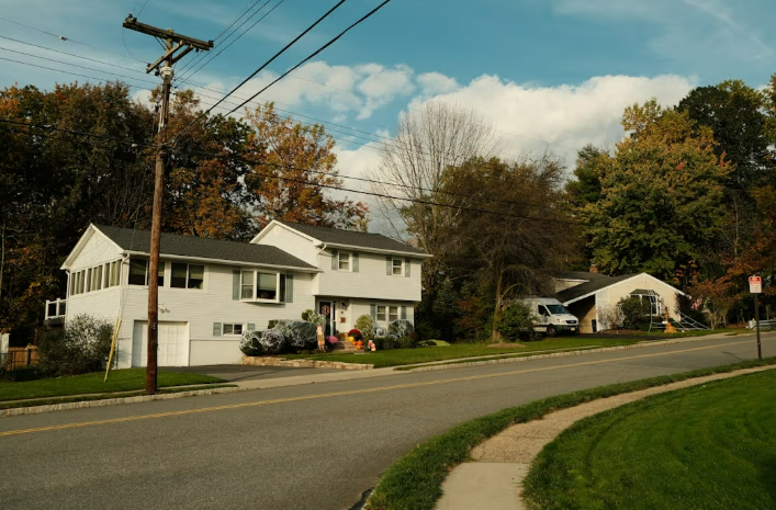 Waste hauler truck with driver collecting compostable yard waste in lawn and leaf bags from a residential area.