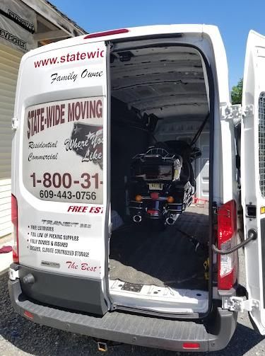 White van with open back doors, a scooter inside; State-Wide Moving logo on the back.