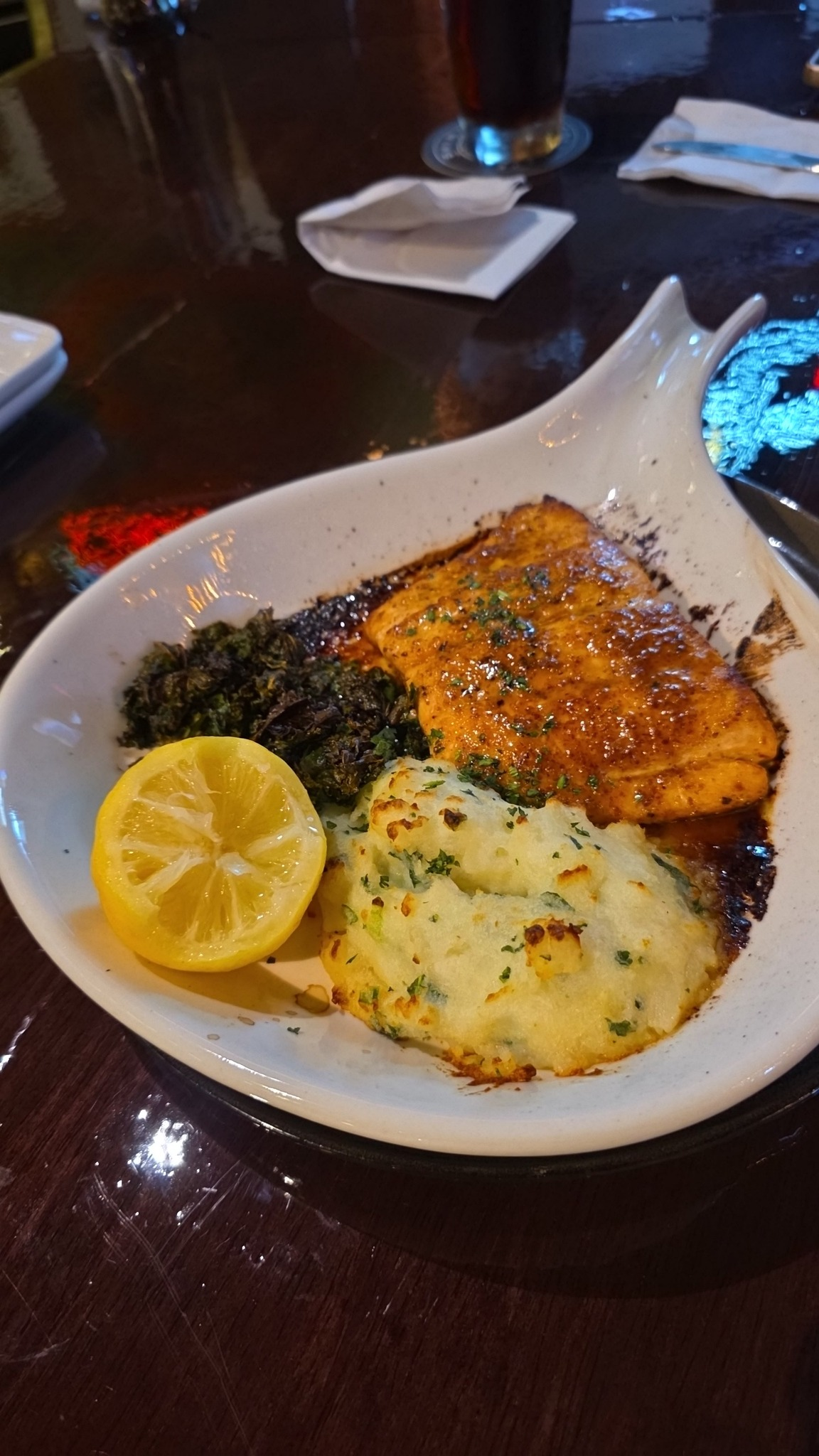 Grilled fish with lemon slices and rice in a white bowl on a dark restaurant table