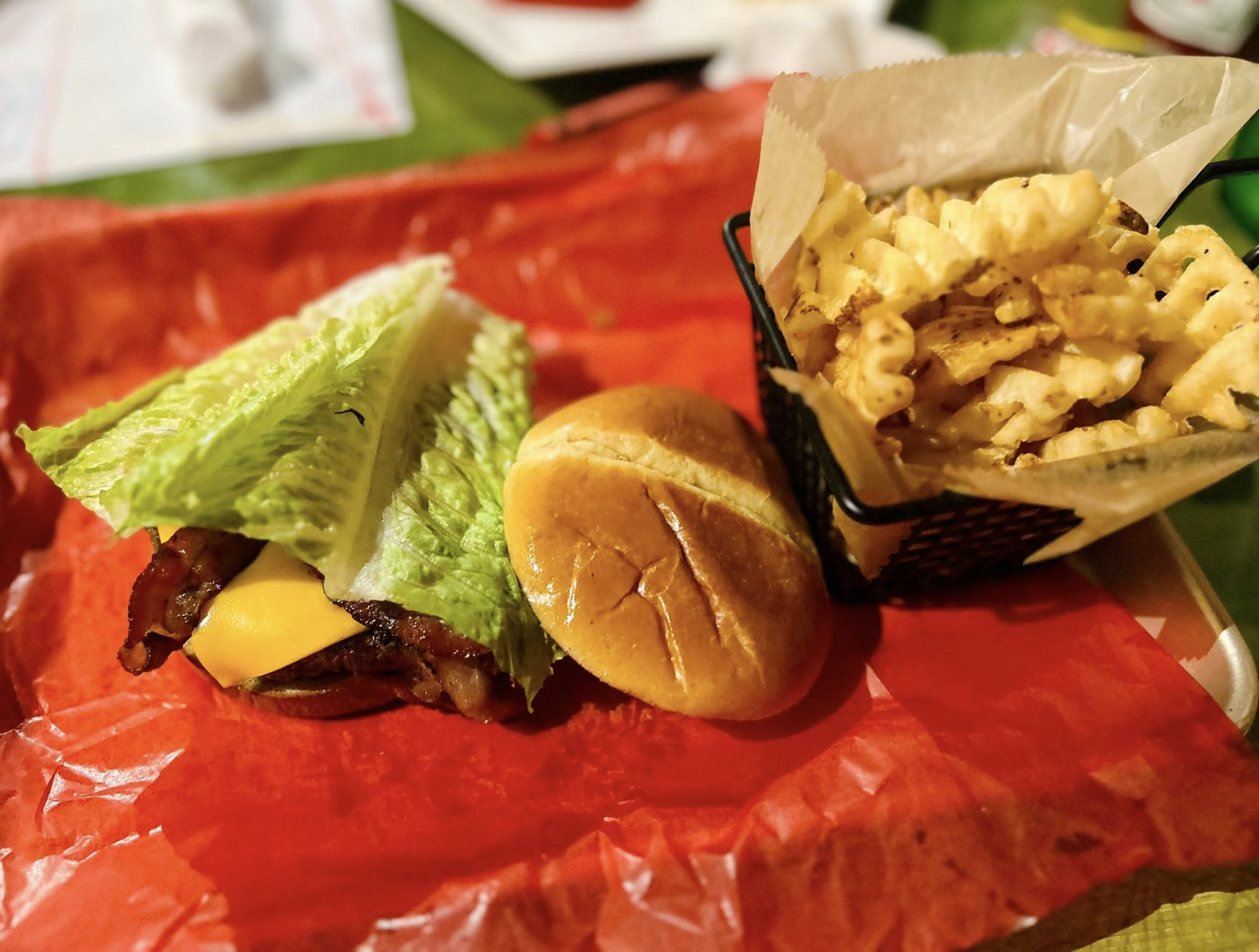 Burger, lettuce, and fries on red paper, with a small container of fries on the side.