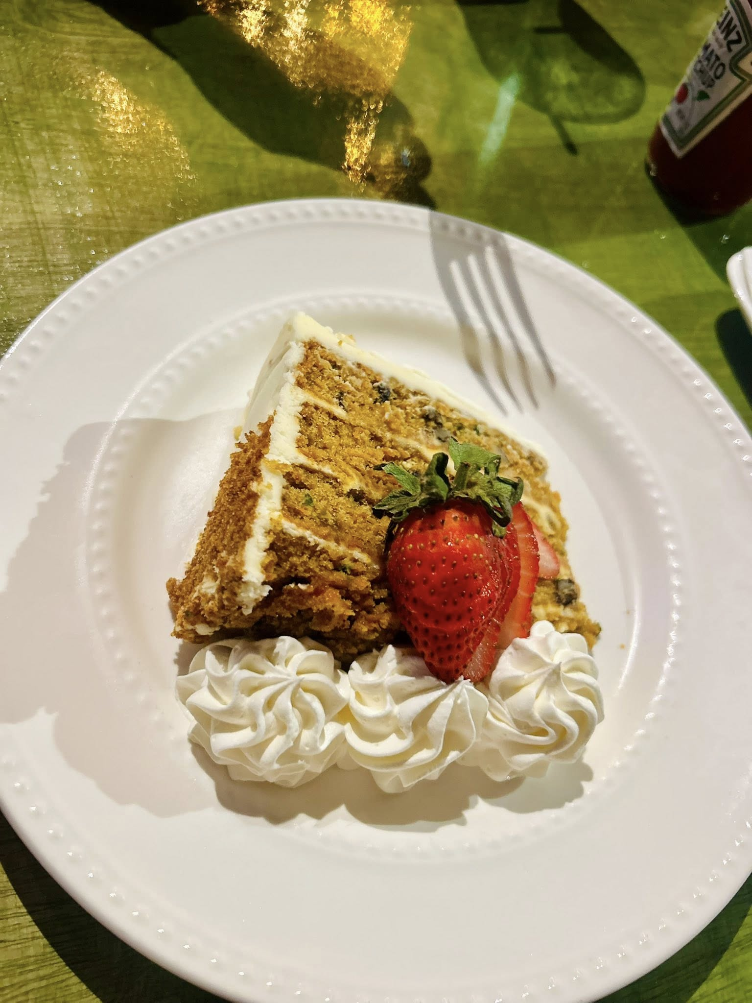 Slice of cake on a white plate with whipped cream and a strawberry garnish