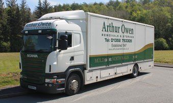 White Arthur Owen Removals delivery truck parked on roadside with green fields and trees in the background