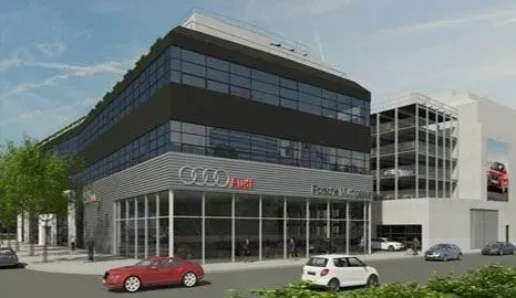 Modernes Bürogebäude aus Glas mit davor geparkten Autos und Beschilderung an der Fassade