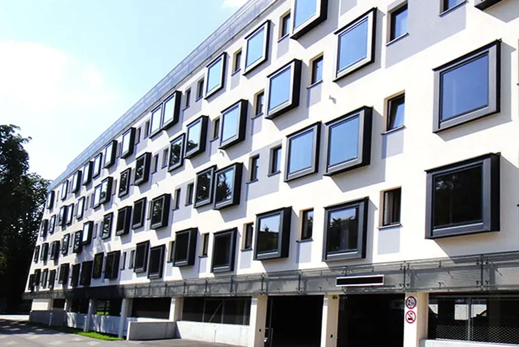 Modernes weißes Gebäude mit vielen schwarz gerahmten Fenstern entlang einer Straße