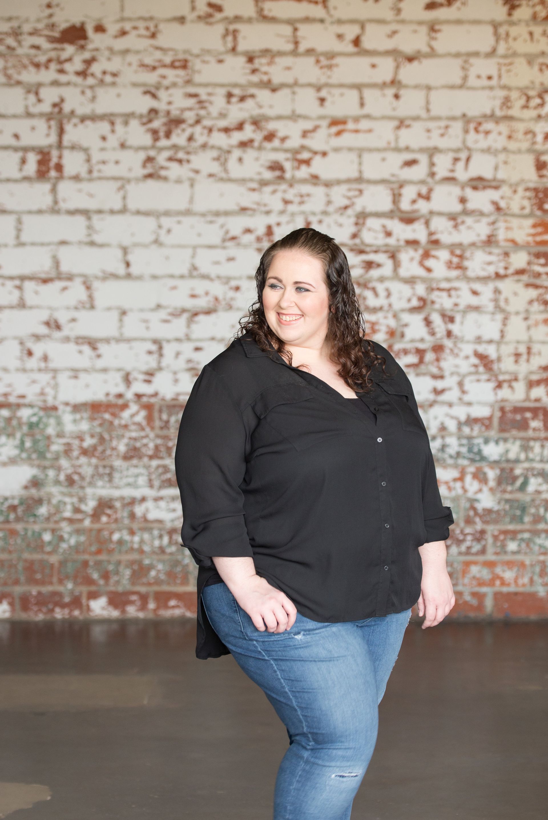 portrait of full figure woman looking to the left side smiling with a relaxed and natural pose.