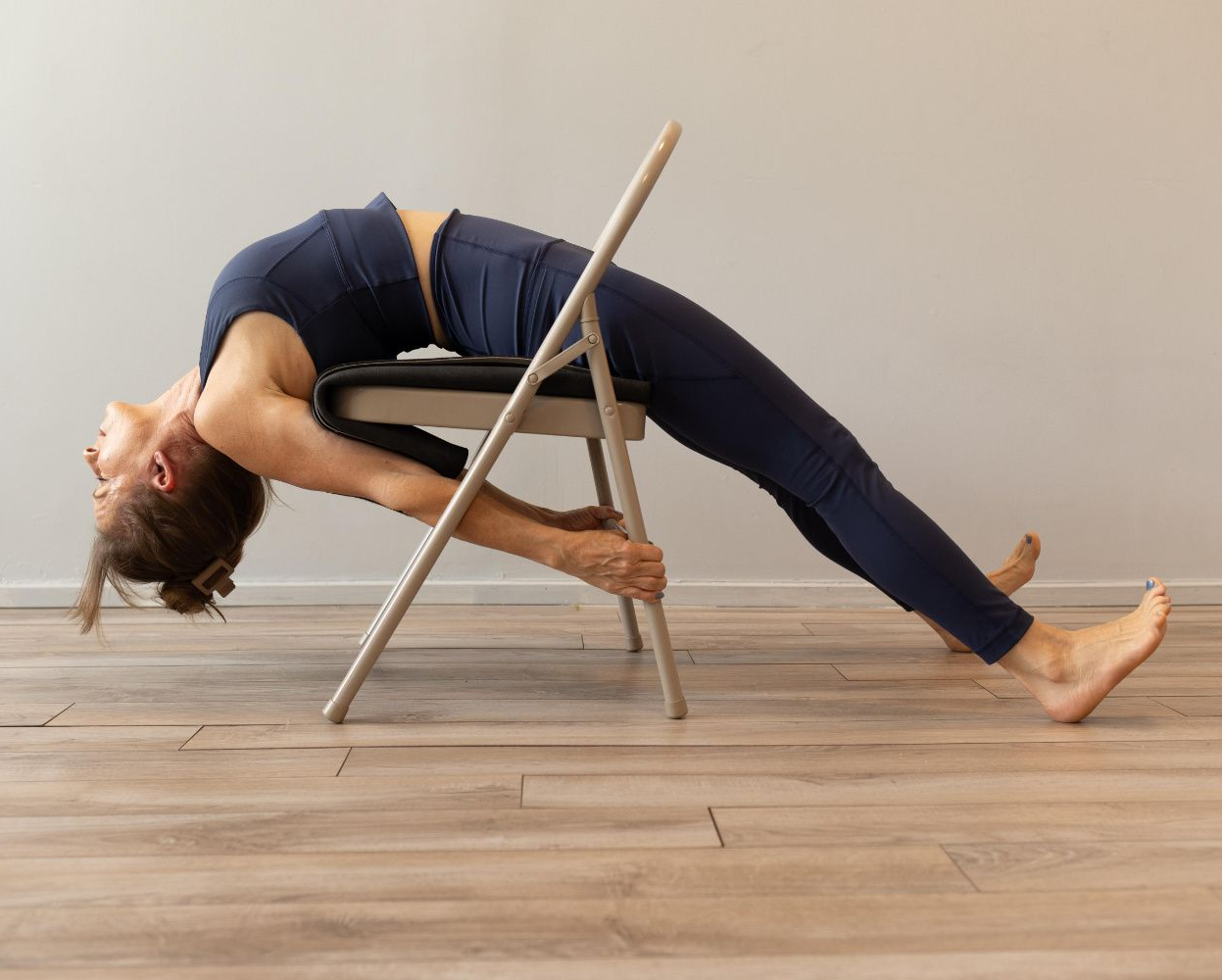 A woman is doing a yoga pose in front of potted plants