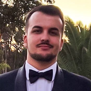 A man with a beard is wearing a tuxedo and bow tie.