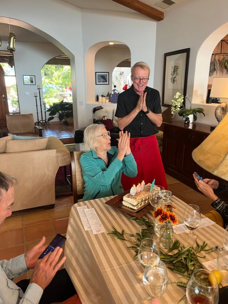 A group of people are sitting around a table with a cake on it.