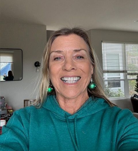 A woman in a green hoodie is smiling for the camera.