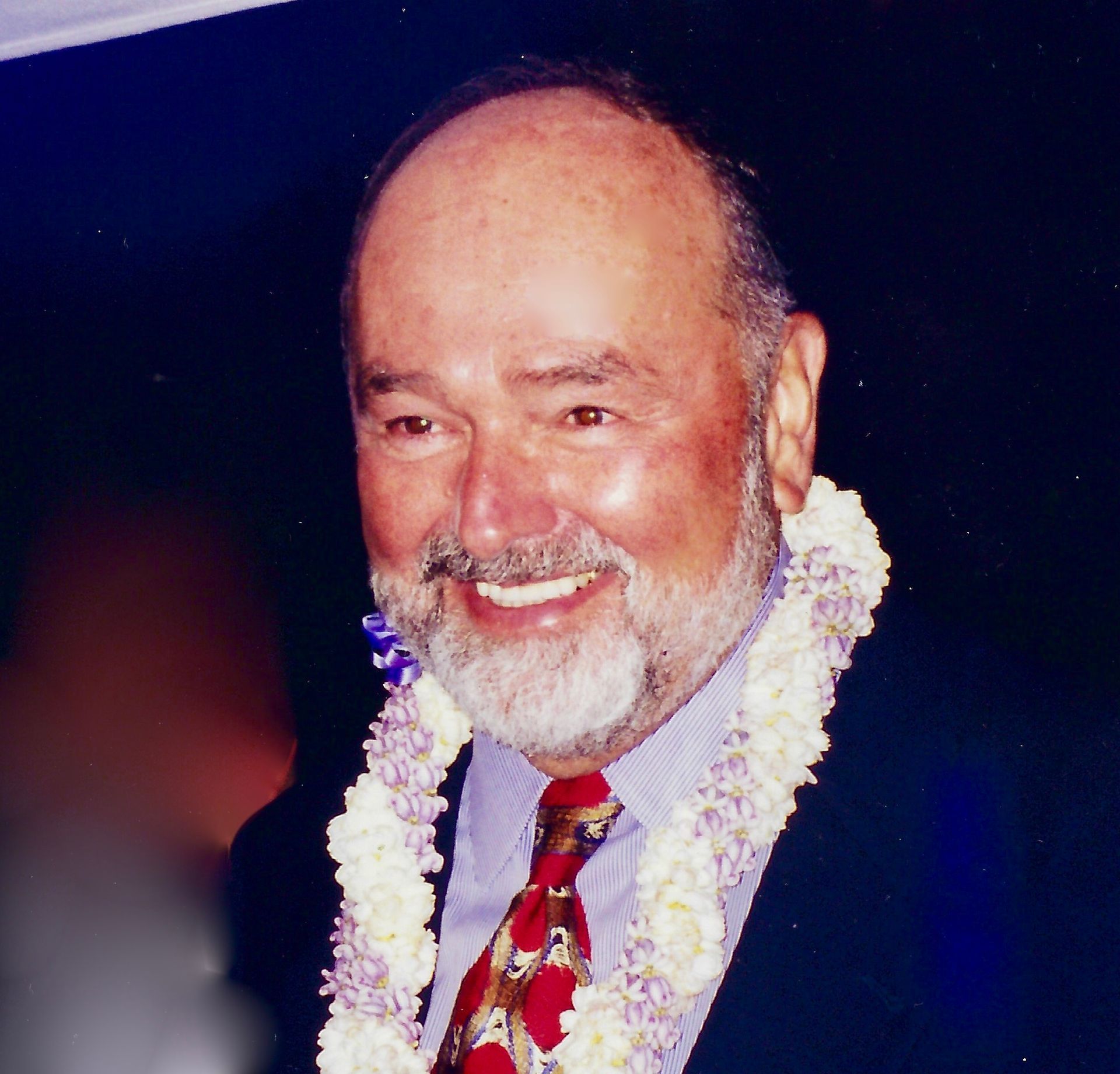 A man with a beard is wearing a lei around his neck
