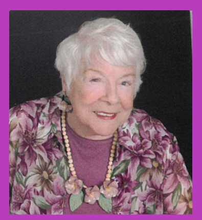 An elderly woman wearing a purple floral shirt and necklace