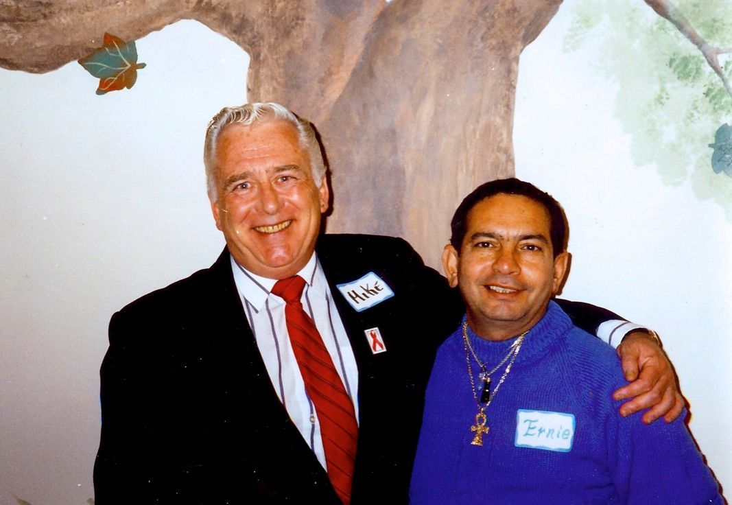 Two men posing for a picture with one wearing a name tag that says eric
