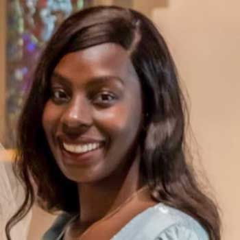 A close up of a woman 's face smiling in front of a stained glass window.