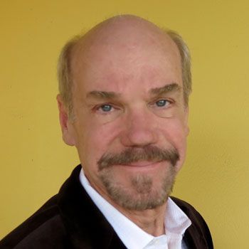 A bald man with a beard wearing a suit and white shirt
