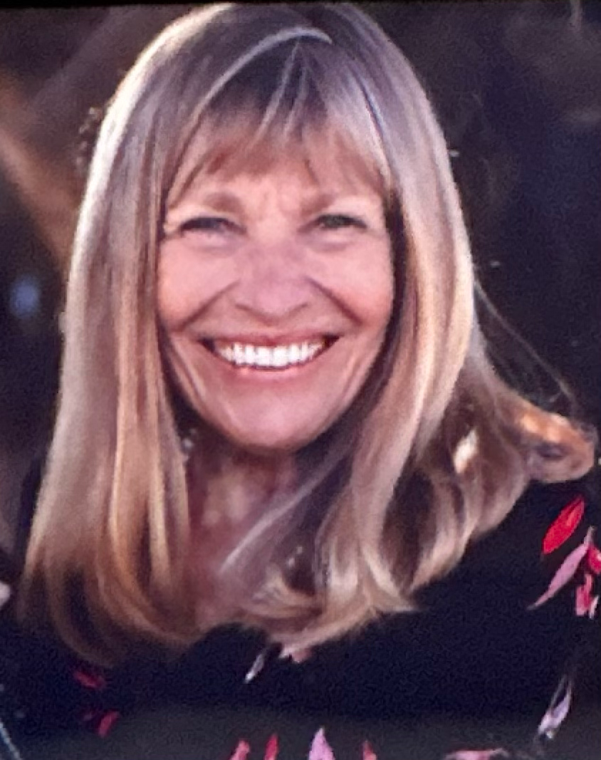 A woman with long blonde hair is smiling for the camera