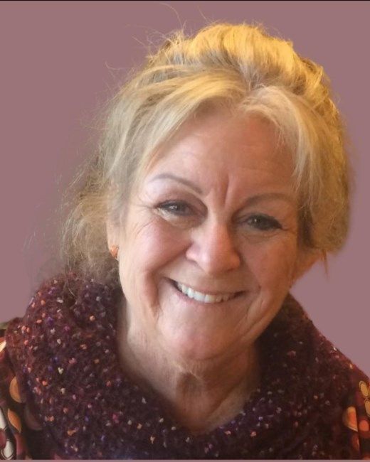 A woman is smiling and wearing a scarf around her neck