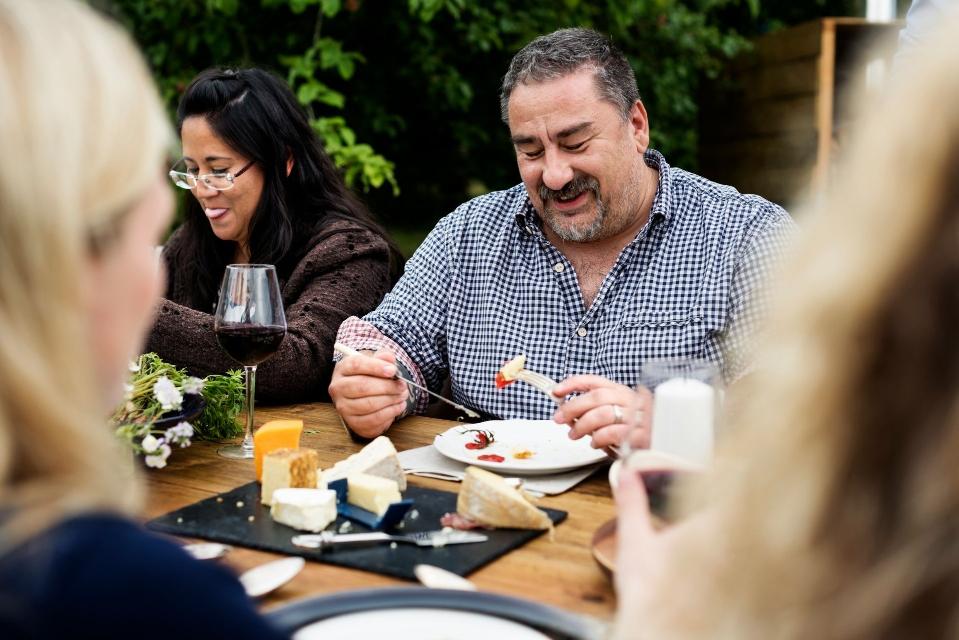 A group of people are sitting at a table eating food and drinking wine.