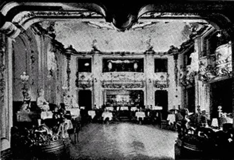 Crowded ornate ballroom with seated guests and a large fireplace at the back