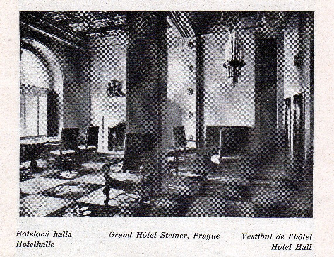 Elegant hotel lobby with armchairs, patterned floor, and tall windows in black-and-white.