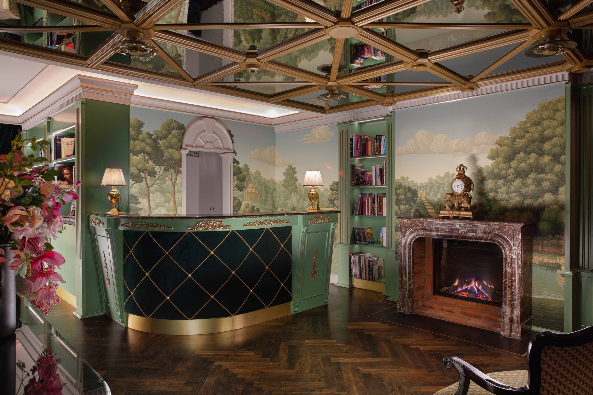Elegant library lounge with green walls, ornate ceiling, bookshelves, and a lit fireplace