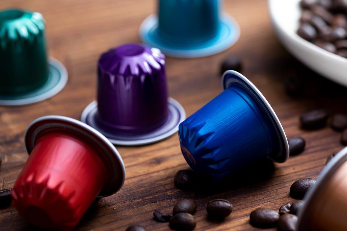 Colorful coffee pods scattered on a wooden table with coffee beans nearby