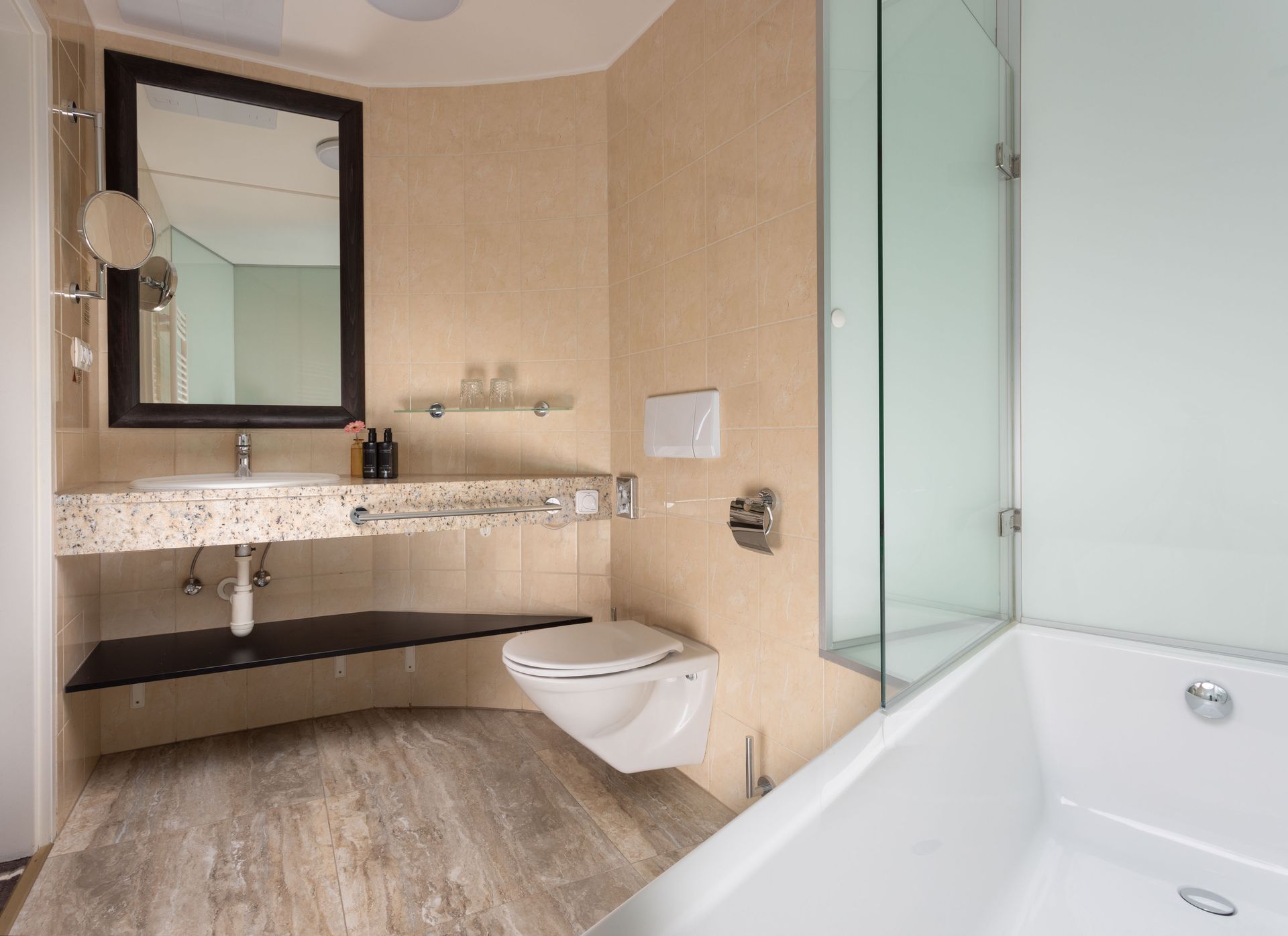 Modern beige bathroom with sink, mirror, wall shelf, toilet, and glass shower beside a bathtub